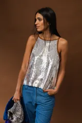 Top sin mangas cubierto de lentejuelas plateadas, con diseño largo y ribetes de cuero en los bordes.