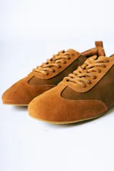 Championes de estilo urbano confeccionados en una combinación de cuero texturizado y gamuza en tonos marrones, con suela plana y diseño minimalista.