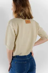 Sweater de punto color tostado con hilos metalizados, de corte recto, escote redondo y mangas cortas con puño ajustado.
