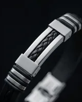 Pulsera masculina de diseño moderno, combinando eslabones de acero inoxidable con una banda central de goma negra trenzada. Cuenta con un cierre de seguridad metálico integrado.
