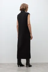 Vestido midi de tejido de punto, color negro, sin mangas, con cuello alto y tajo frontal en la falda.