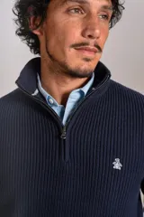 Sweater de punto acanalado color azul marino, con cuello alto y cierre frontal parcial. Presenta el logo de la marca bordado en el pecho y puños con terminación elástica.