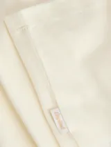 Remera de manga corta color blanco off-white, con detalles en color azul oscuro en el cuello redondo y en los bordes de las mangas.