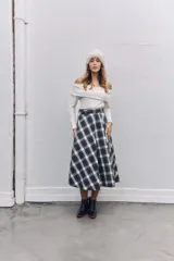 Falda midi de corte acampanado con estampado de cuadros escoceses en tonos blanco y negro. Presenta un diseño de cintura alta con detalle de solapa y cierre lateral.