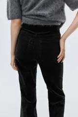 Pantalón acampanado de pana color negro, de tiro alto, con cierre de botón y bolsillos de parche delanteros y traseros.