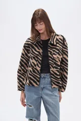Campera estilo camisa (shacket) cropped, con cuello, cierre frontal y dos bolsillos con tapa en el pecho. Presenta un estampado de cebra en tonos beige y negro.