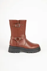 Bota corta de cuero sintético color marrón, con punta redonda, plataforma tractor negra y apliques de tachas, hebilla y argolla.