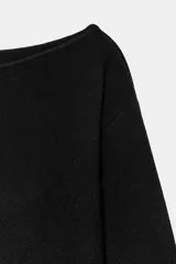 Jersey de punto negro con cuello barco y mangas largas amplias. Presenta un diseño ajustado en la cintura con un cinturón fino integrado que incluye una hebilla metálica dorada.