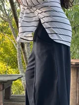 Remerón de manga larga, color blanco con rayas horizontales negras, corte oversize con tajos laterales y bajo redondeado.