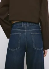 Jeans de denim azul oscuro con corte ancho y recto, tiro medio y dobladillo vuelto en los bajos.