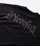 Remera oversize de tejido tipo gamuza sintética negra, con cuello redondo, manga corta y bordado de cruz gótica en el pecho.
