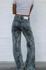 Jean de mujer de corte acampanado, tiro alto, color gris con efecto acid wash. Presenta costuras verticales en la parte delantera y bolsillos de parche.