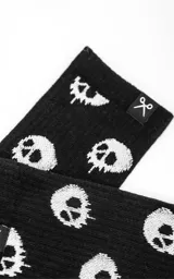 Medias negras con estampado de calaveras blancas en contraste, tiro medio con ribete elástico y pequeña etiqueta con el logotipo de unas tijeras en el borde superior.