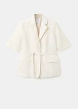 Blazer corto de mezcla de lino en color beige con rayas sutiles, de corte recto, cuello con solapa de muesca, mangas tres cuartos, cierre frontal de un botón y bolsillos con solapa.