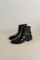 Bota corta de cuero marrón con panel trasero de gamuza en tono más oscuro, suela de goma negra y taco cuadrado bajo.