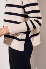 Sweater beige con rayas horizontales negras, de corte holgado y mangas largas.