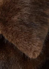 Chaqueta de piel sintética en color marrón chocolate, con cuello solapa, cierre frontal y mangas largas. Presenta una silueta recta y un acabado suave.