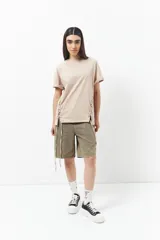 Remera blanca de algodón con cordones ajustables a los laterales, manga corta y cuello redondo.