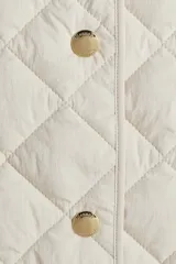 Chaleco guateado color beige, con cuello redondo, cierre frontal con botones a presión y dos bolsillos de parche en la parte delantera. Sin forrar.