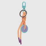 Llavero de cuerda trenzada en tonos naranja y blanco, con mosquetón y argolla metálica color turquesa. Incluye un dije circular de silicona en color turquesa con centro lila y logo grabado, además de punteras de goma color violeta.