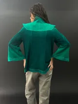 Buzo verde esmeralda de lana merino con cuello alto y mangas largas. Presenta dos texturas: afieltrada en cuello, mangas y ruedo, y tejido merino superfino en el delantero y la espalda.