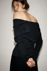 Jersey de punto con cuello fluido, manga larga y detalle de botones en la parte frontal.