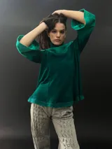 Buzo verde esmeralda de lana merino con cuello alto y mangas largas. Presenta dos texturas: afieltrada en cuello, mangas y ruedo, y tejido merino superfino en el delantero y la espalda.
