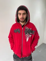 Campera reversible con cierre frontal, confeccionada en algodón de alto gramaje con estampa plastisol y bordado con aplique en un lado, y tela polar de pelo largo en el reverso. Presenta diseño oversize, capucha integrada y puños acanalados.