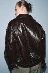 Chaqueta de efecto cuero con acabado brillante, cuello de solapa con aplicación de pelo sintético extraíble, cierre frontal cruzado con botones, mangas largas con puños ajustables y bajo elástico. Cuenta con forro interior acolchado.