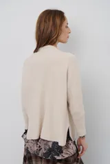 Polera de tejido de punto en color beige, con cuello alto y mangas largas con puños acanalados.