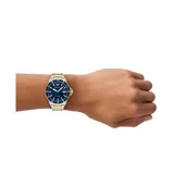 Reloj Emporio Armani con caja de acero inoxidable bicolor de 42mm y esfera azul sunray. Cuenta con manecillas e índices luminosos, ventana de fecha y resistencia al agua de 10 ATM. La correa es de acero bicolor.
