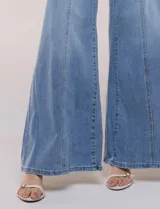 Pantalón jean de tiro alto con calce ajustado en la cadera y pierna de corte ancho tipo wide leg. Presenta costuras verticales en el frente y bolsillos aplicados.