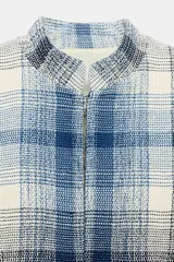 Blazer de corte peplum con cuello redondo y manga larga. Confeccionado en tejido de textura con mezcla de algodón y lino, presenta un estampado de cuadros en tonos azules y blancos. Incluye forro interior y cierre frontal mediante ganchos metálicos.