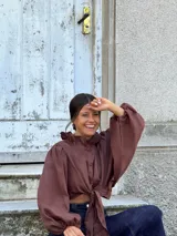 Camisa de lino color negro, con cuello con volados, mangas largas amplias y diseño con nudo frontal.