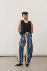 Pantalón de corte ancho y relajado con rayas verticales multicolor en tonos azul, marrón, amarillo, blanco y negro.