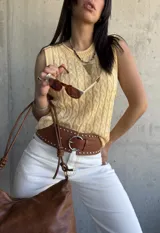 Chaleco amarillo de hilo tejido con diseño de trenzas, sin mangas y cuello redondo.