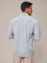 Camisa de manga larga para hombre, confeccionada en algodón con efecto peach (textura suave). Presenta un estampado de cuadros vichy en tonos azul marino y blanco, cuello con botones y un bolsillo de parche en el pecho izquierdo.