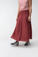 Falda larga beige de corte evasé, con diseño fluido y detalles de costuras verticales en la parte delantera.