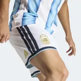 Short de fútbol blanco, corte clásico, con cintura elástica y cordón ajustable. Presenta detalles en azul marino y celeste en los bordes inferiores y el escudo de la AFA en dorado.