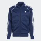 Campera deportiva Adidas de corte ajustado, color azul marino con las icónicas tres tiras blancas en las mangas y logo del Trifolio bordado en el pecho. Cuenta con cierre frontal, cuello alto acanalado, bolsillos laterales con cierre, y puños y dobladillo acanalados.