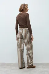 Pantalón de corte recto y tiro medio, con diseño de rayas verticales en tonos marrón, blanco y azul. Cuenta con cierre frontal y bolsillos laterales.