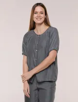 Blusa de calce relajado de lyocell en tono azul denim, con cuello a la base y cierre frontal de botones metálicos. Tiene mangas cortas abullonadas con puños elásticos.