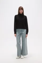 Buzo de manga larga color negro, con cuello alto tipo mock neck y corte holgado. Presenta costuras tipo raglán en los hombros.