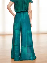 Mono de vestir verde esmeralda con estampado abstracto, escote en V, mangas cortas y pantalón palazzo con aberturas laterales.