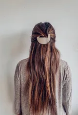 Broche para el pelo dorado con forma semicircular.