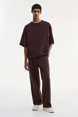 Remera de punto de algodón pesado color marrón oscuro (bordó/ciruela), con cuello redondo ribeteado, hombros caídos y corte oversized.