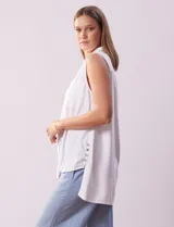 Blusa blanca sin mangas de lino, marca Zac & Rachel. Cuello con solapa, escote en V y abertura central con botones. Delantera con bolsillos aplicados. Laterales con botones aplicados.