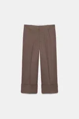 Pantalón de vestir color marrón oscuro, tiro alto, corte recto y ancho, con pliegues marcados al frente y bajo con vuelta ancha.