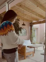 Sweater de punto tejido a mano con diseño nórdico en el canesú, combinando tonos crudo, marrón y negro. Presenta cuello redondo y mangas largas, con una textura suave y abrigada.