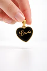 Dije en forma de corazón de acero dorado con esmalte negro y la palabra Love en relieve.